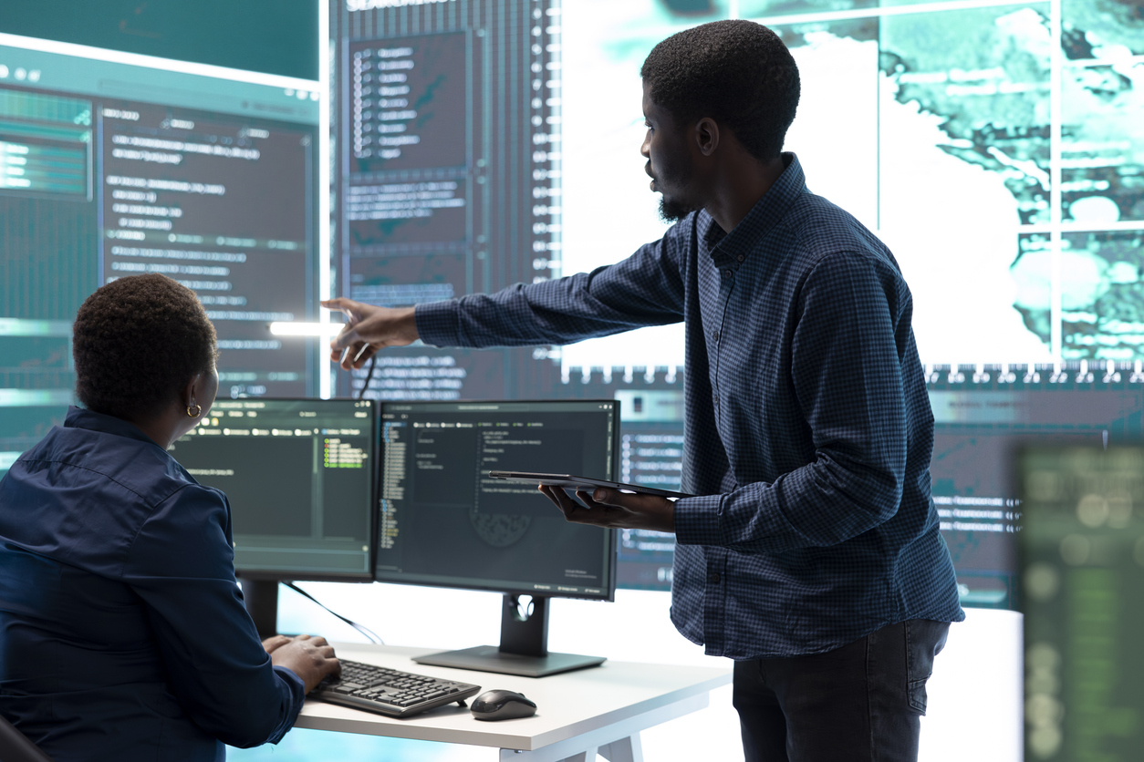 A cyberdefense team reviews code on a large monitor.