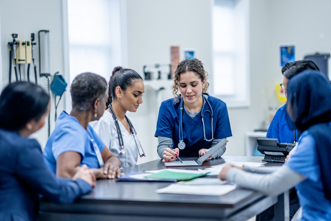 A group of nurses meets around a conference table.