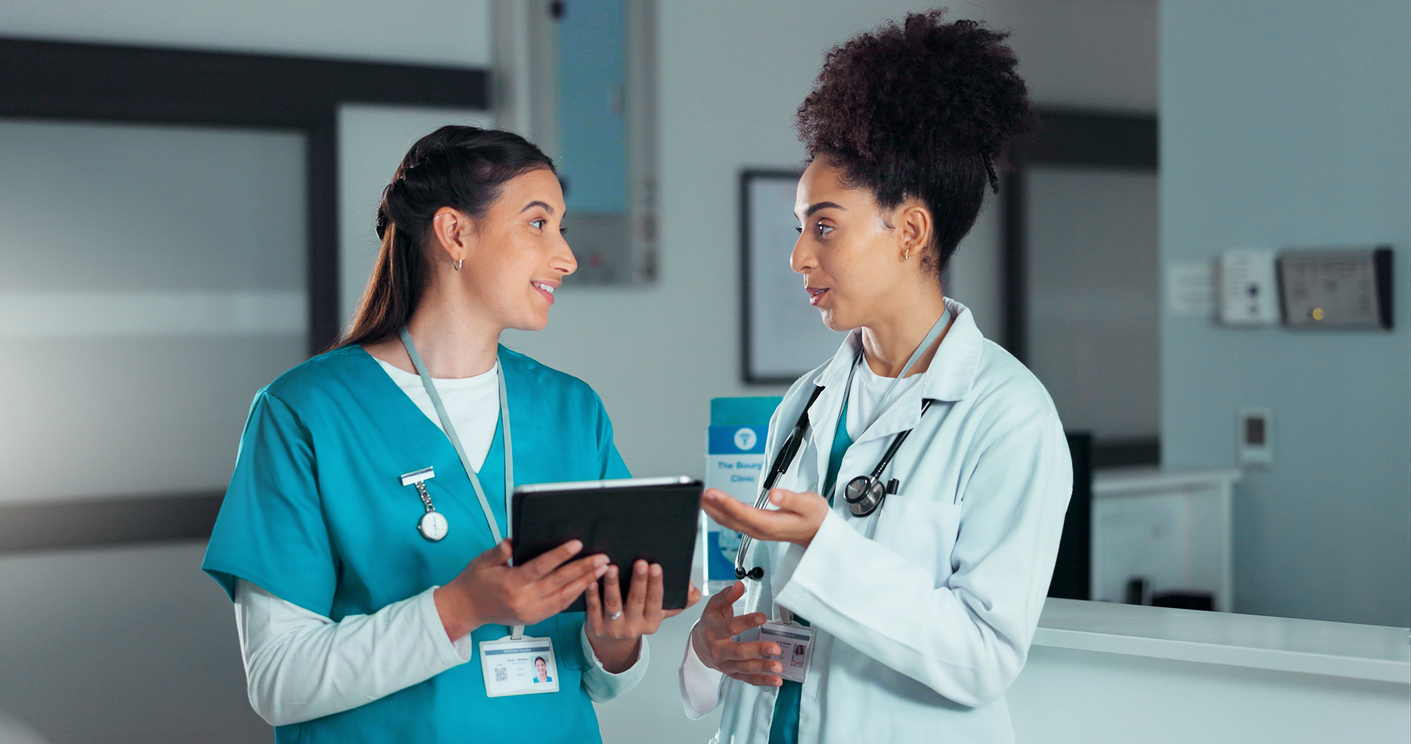 A nurse talks with a physician in a hospital corridor.
