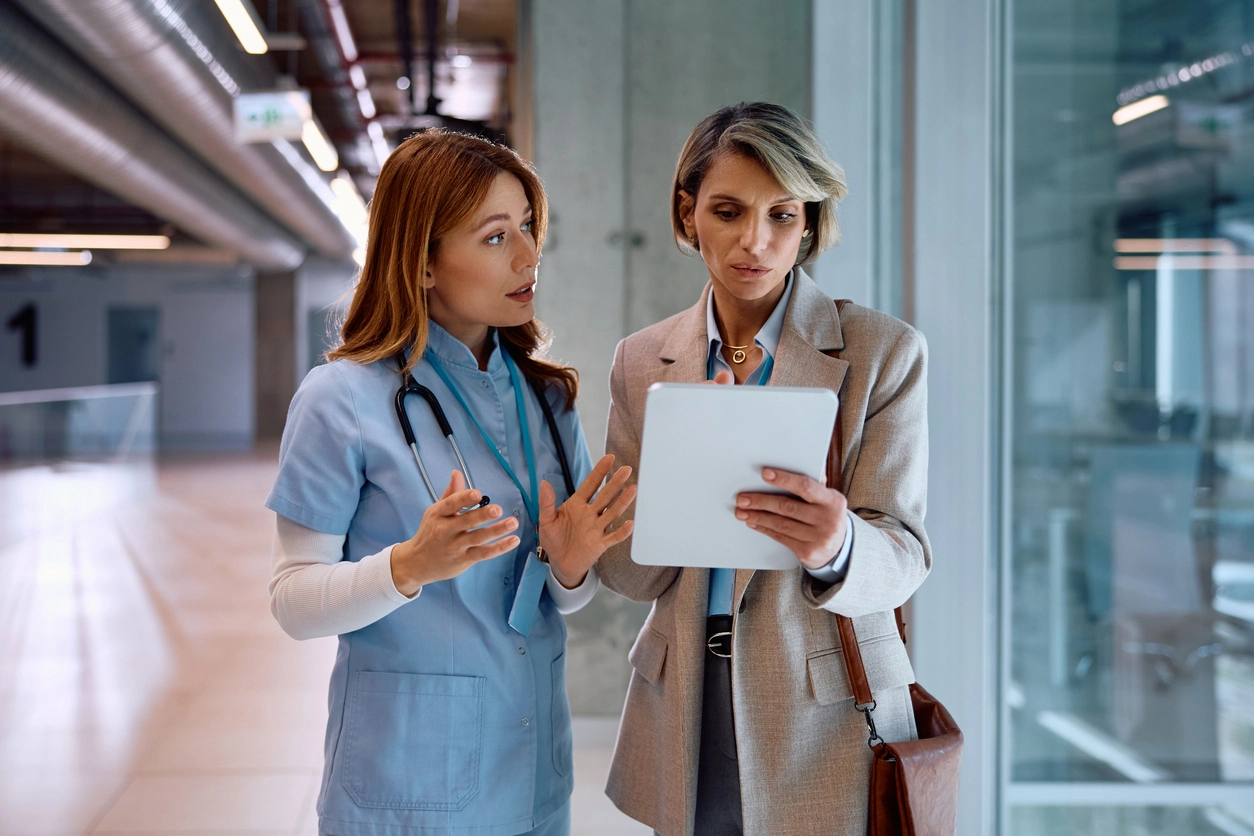 Nurse leader holding a tablet talking to a nurse. 