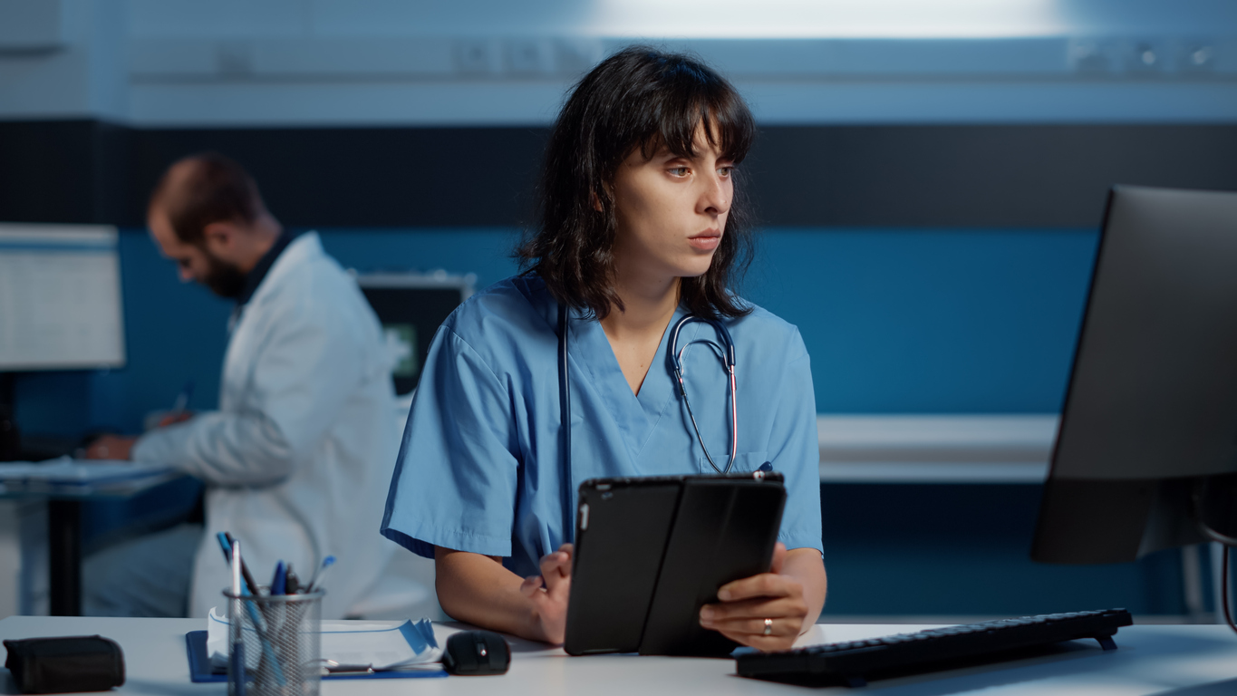 A nurse works on a tablet in a medical office.