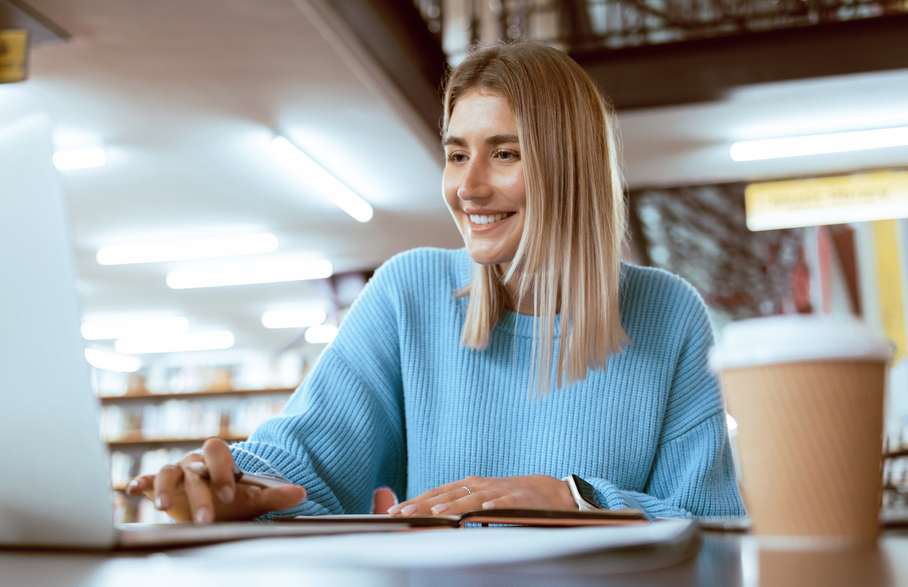 A smiling online student works on a laptop.