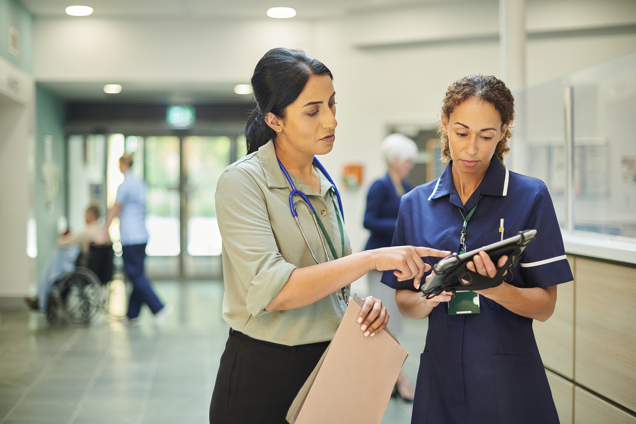 A director of nursing meets with another medical professional in a medical facility. 