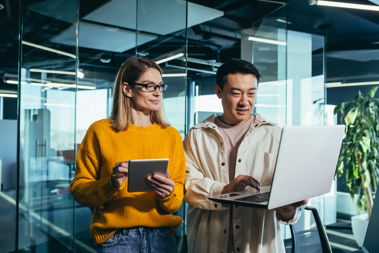 Two cybersecurity professionals consult a laptop.